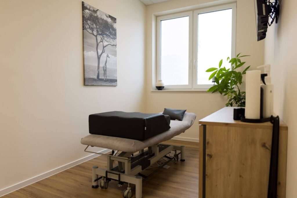Heller Behandlungsraum mit Therapieliege und Fenster